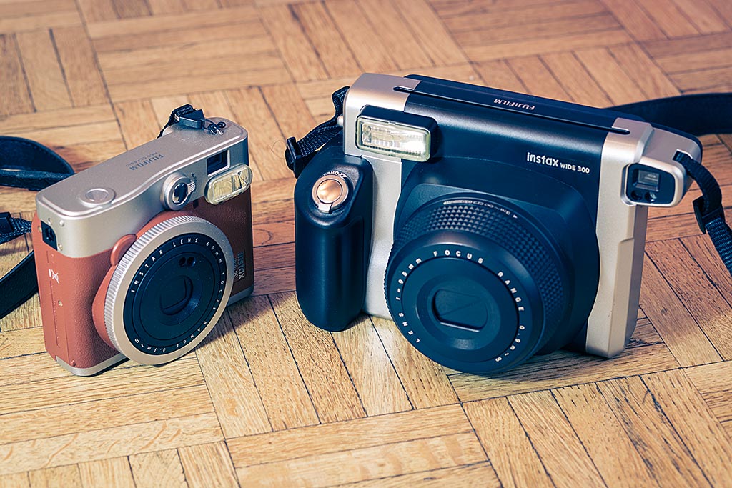 L'Instax Mini 90 Neo Classic et l'Instax Wide 300 côté à côte. Le Wide fait clairement figure de grand frère dans la famille Instax.