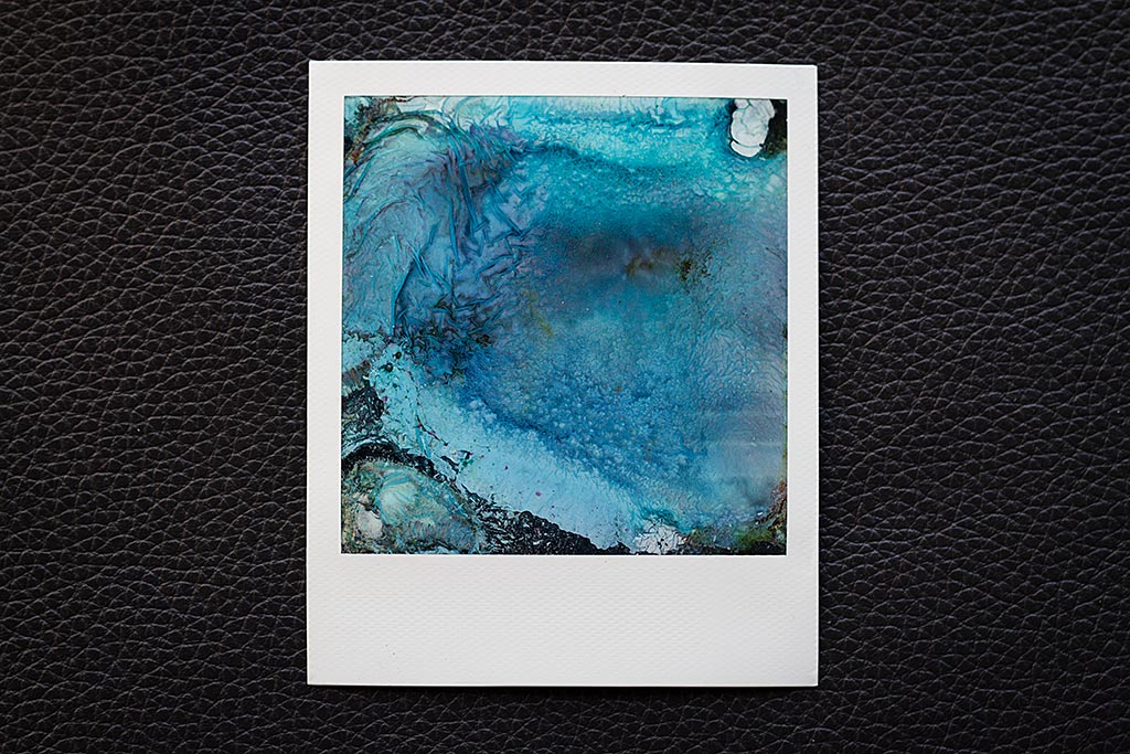 Cela prend du temps, mais au contact de l’eau, le dos du polaroid finit par se désagréger et troubler l’eau. Ne touchez à rien et laisser la magie (ou la chimie) opérer.